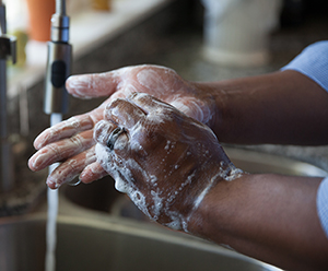 Washing hands with soap and running water.