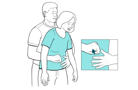 Man behind woman with arms around her waist and detail of his fist and other hand ready to cover fist.